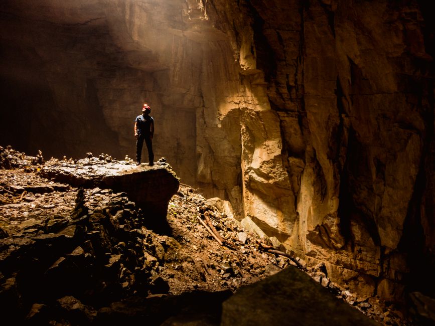 Kayaker inside dark limestone sea cave Mljet Croatia headlamp reflection