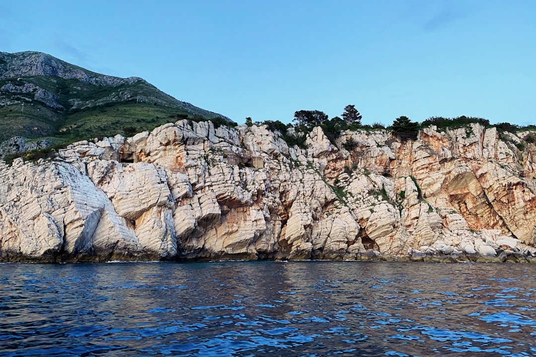 Cyclist resting on coastal road overlooking Adriatic Sea Montenegro dramatic cliffs blue water