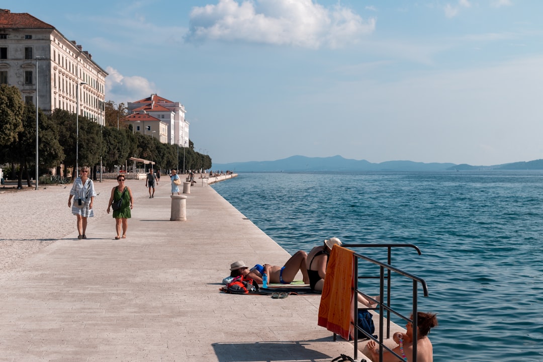 Zadar beach tourists water shoes pebble shore summer day atmosphere