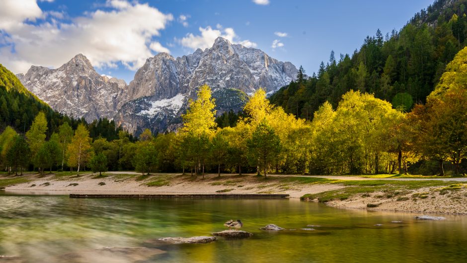 Upper Seven Lake Slovenia alpine tarn blue water Mount Triglav background hikers on trail
