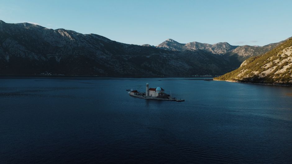 Perast Montenegro bay sunset artificial island silhouetted mountains dark water