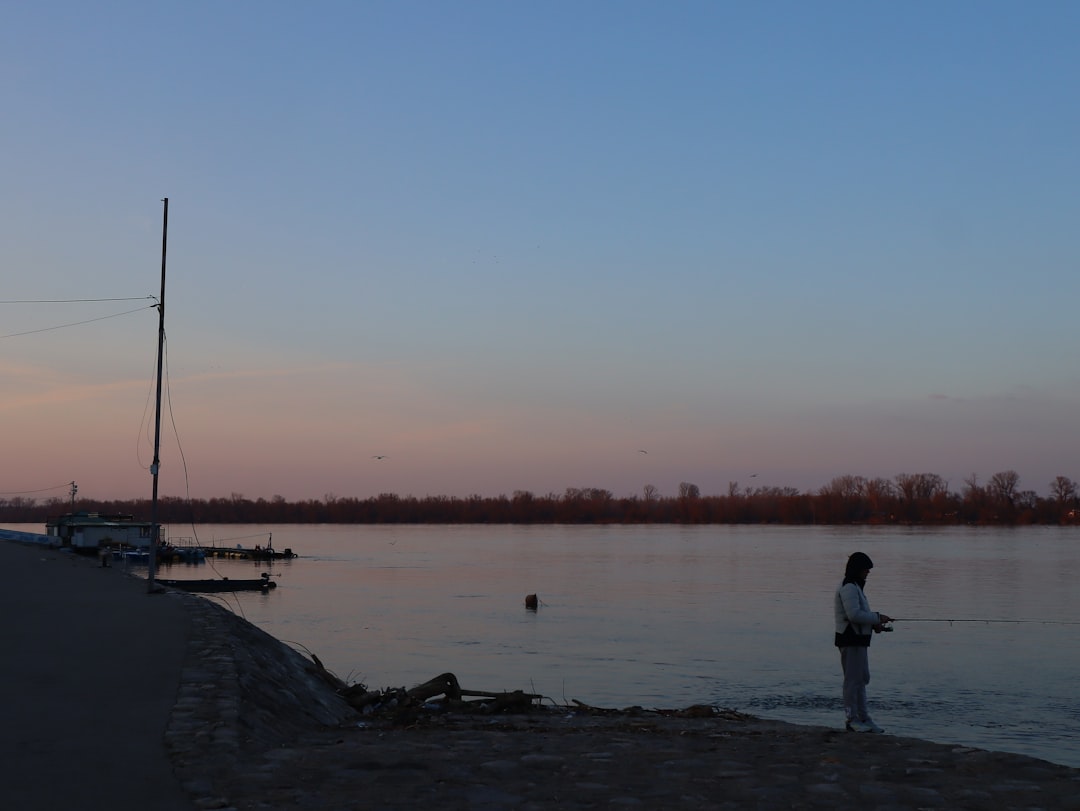Cyclist on flat paved path along Danube River Belgrade Serbia sunset historic bridges