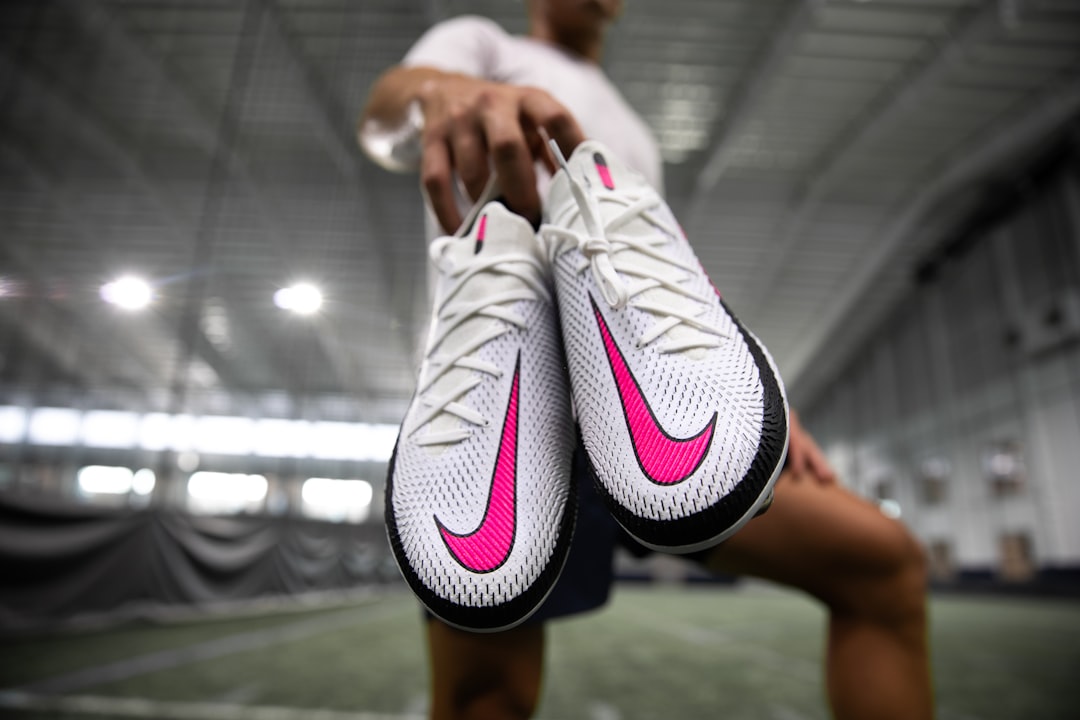 Football player adjusting pink cleats before match