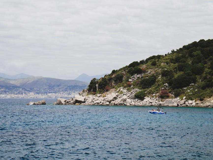 Cyclist on narrow coastal road Albania Riviera turquoise water green mountains village
