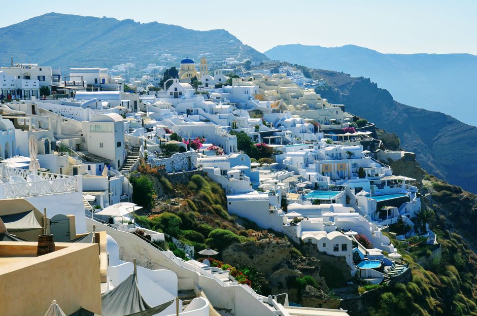 Santorini Kamari black sand beach with blue water and white buildings in background